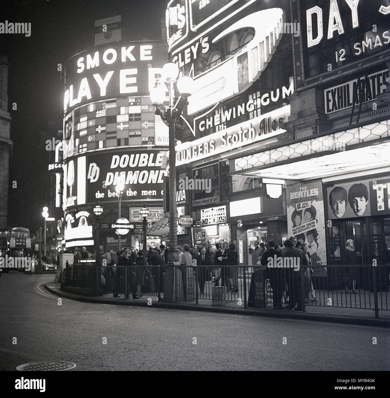 1964, immagine storica, persone fuori dal Pavilion Theatre a Piccadilly Circus, Londra, in attesa di vedere 'A Hard Day's Night', il film con la partecipazione del leggendario gruppo pop britannico, i Beatles, durante l'apice della follia di 'Beatlemania'. La band di Liverpool, Inghilterra, ha trasformato la musica in questa era e il film è stato un grande successo. L'incrocio stradale e lo spazio pubblico sono stati costruiti nel 1819 per unire Piccadilly con Regent Street. Nel West End della città alcuni dei famosi marchi britannici del giorno possono essere visti sui tabelloni pubblicitari, tra cui i giocatori di sigarette e birra Double Diamond. Foto Stock