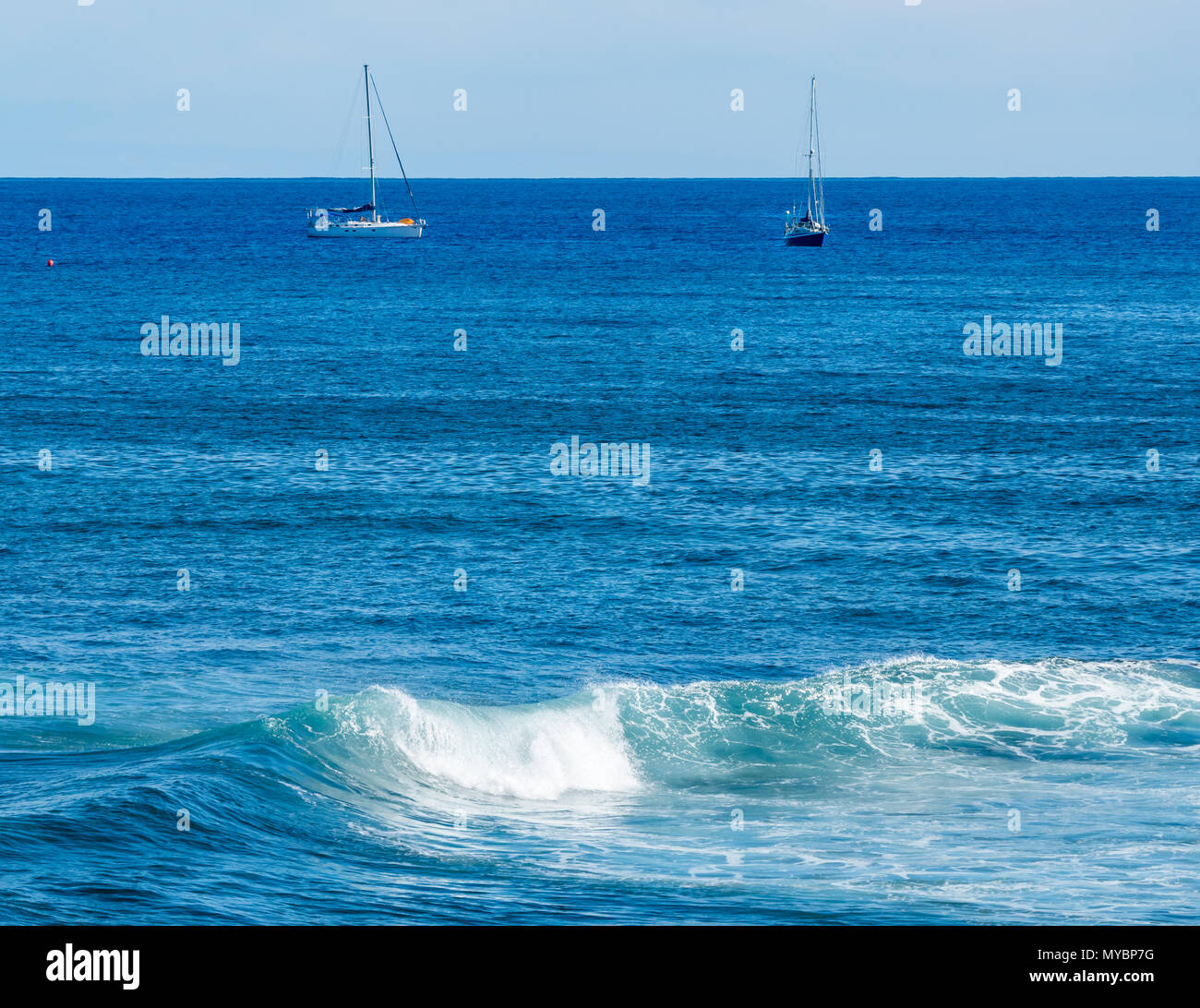 Idilliaca vista sull'oceano Pacifico con barche a vela ancorate e cresta delle onde Foto Stock