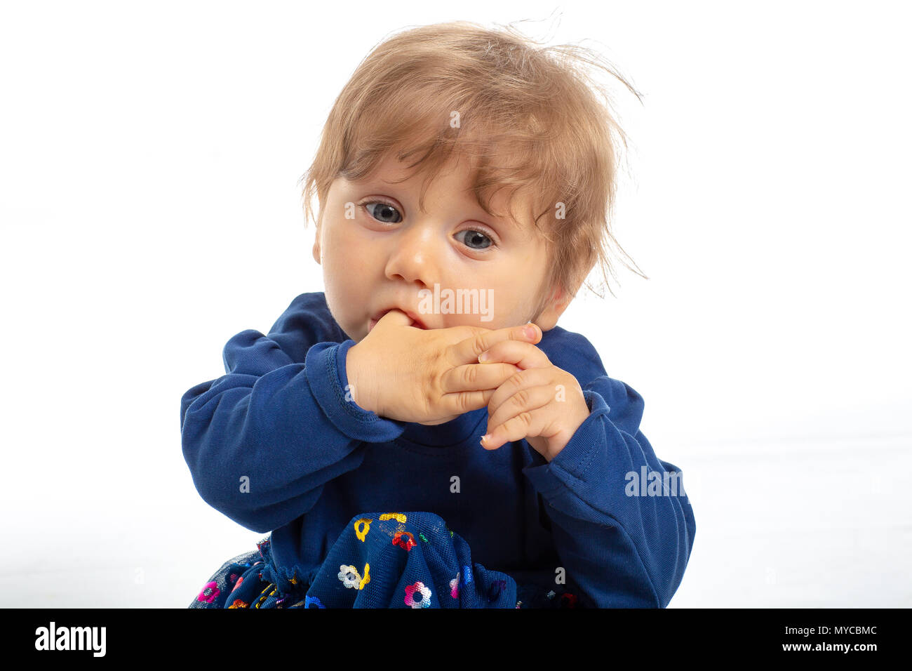 Ritratto di felice bambina di 1 anno con gli occhi blu e il vestito in posa di studio. Sfondo bianco. Concetto di felicità. Foto Stock