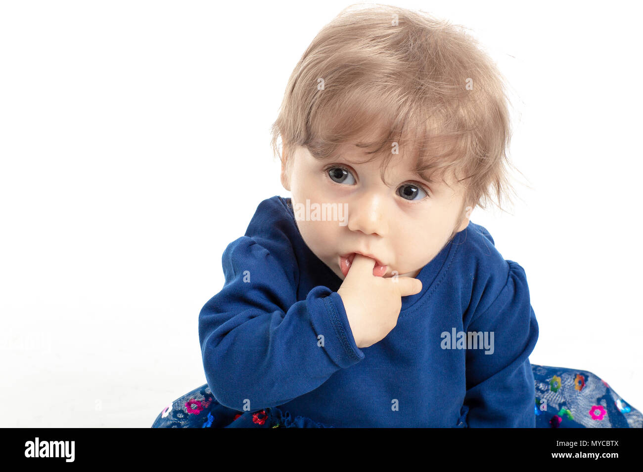 Ritratto di felice bambina di 1 anno con gli occhi blu e il vestito in posa di studio. Sfondo bianco. Concetto di felicità. Foto Stock