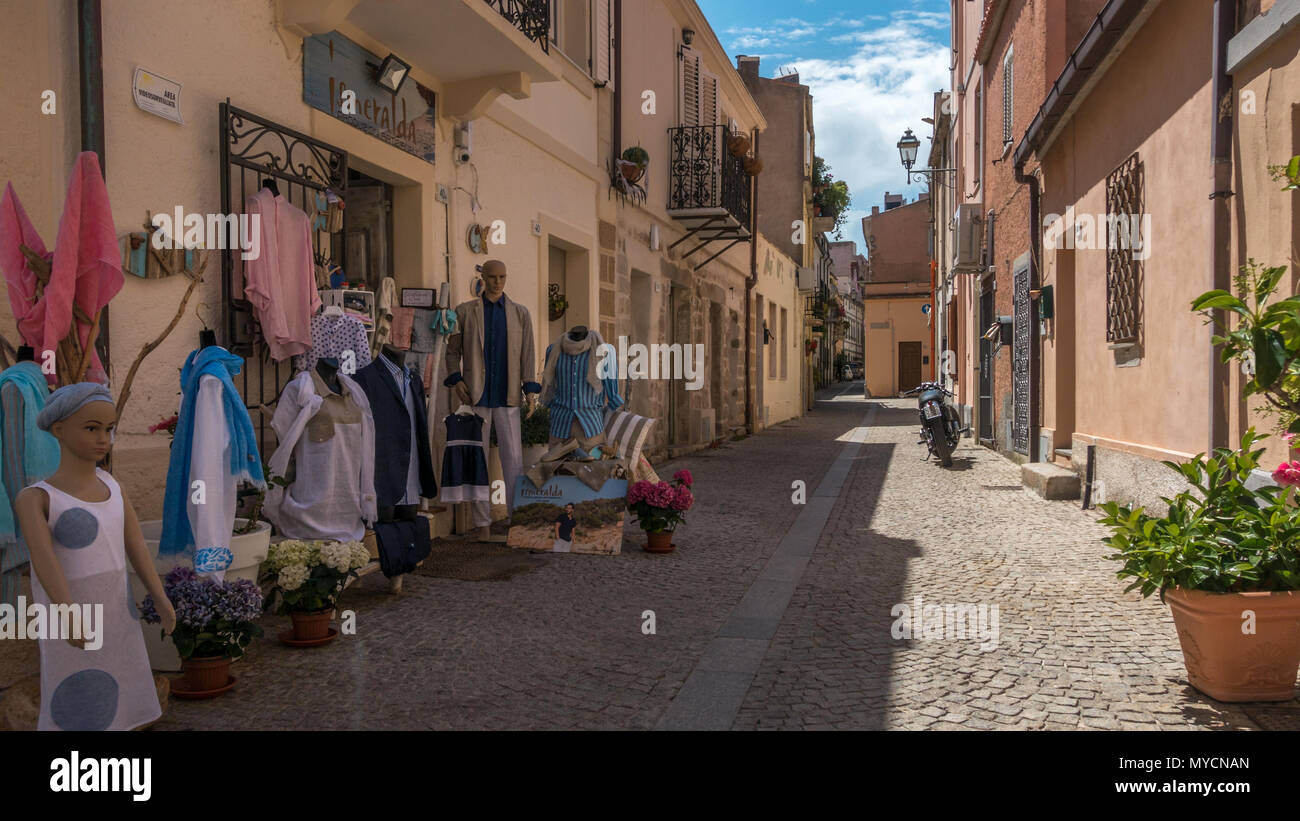 Strade di Olbia città vecchia con locale negozio di abbigliamento la visualizzazione di merci al di fuori, Sardegna Foto Stock
