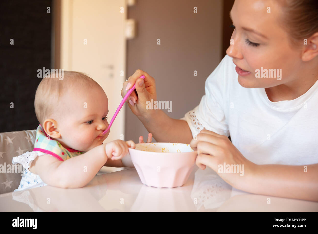 Caring giovane madre alimenta la sua bambina Foto Stock