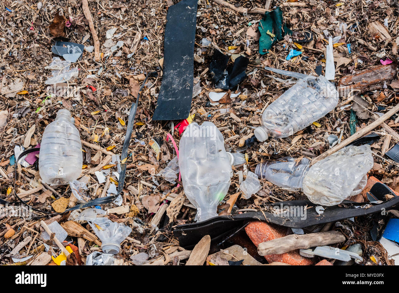 Plastica casuale, rifiuti, rifiuti, detriti e mattoni sparsi sul terreno. Foto Stock