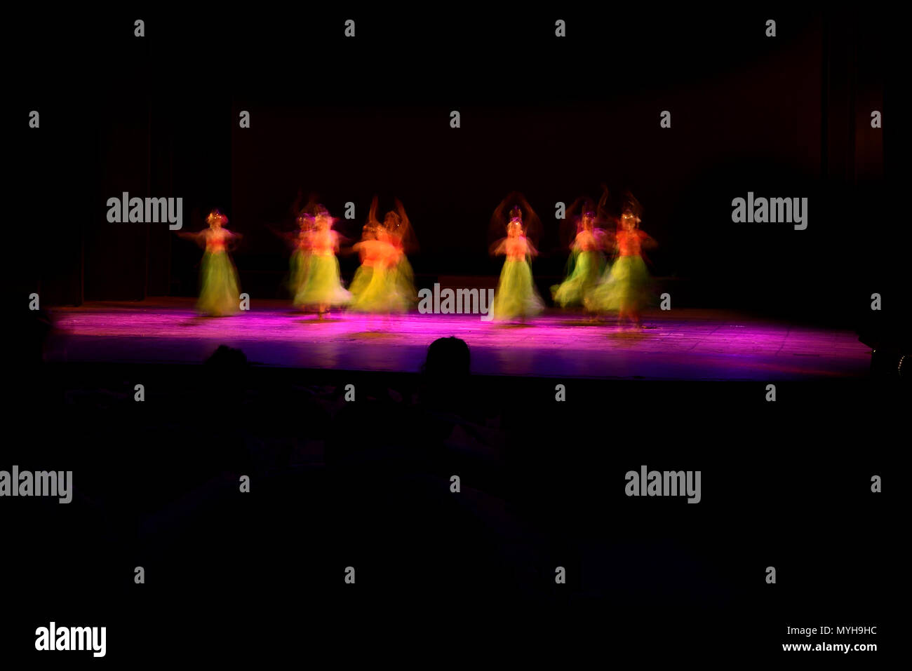 Un gruppo di persone che ballano sul palco su sfondo nero. Foto Stock