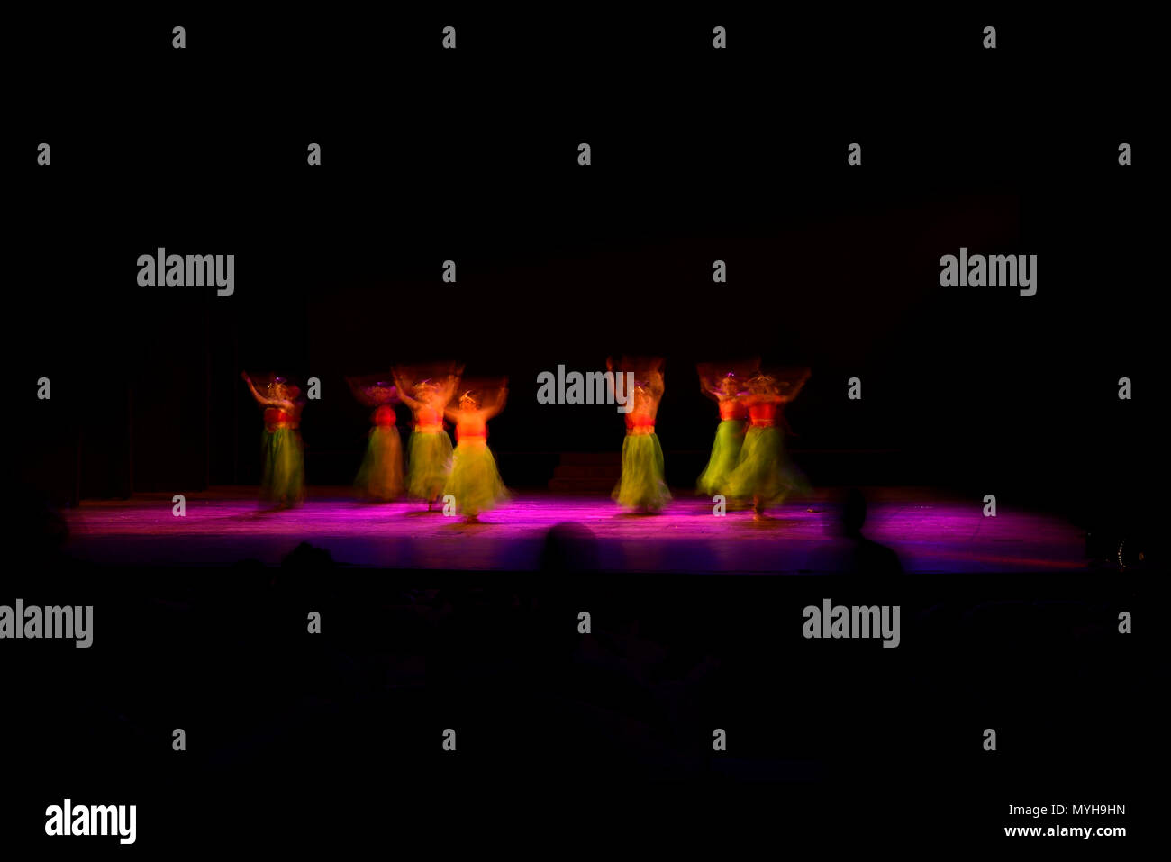 Un gruppo di persone che ballano sul palco su sfondo nero. Foto Stock