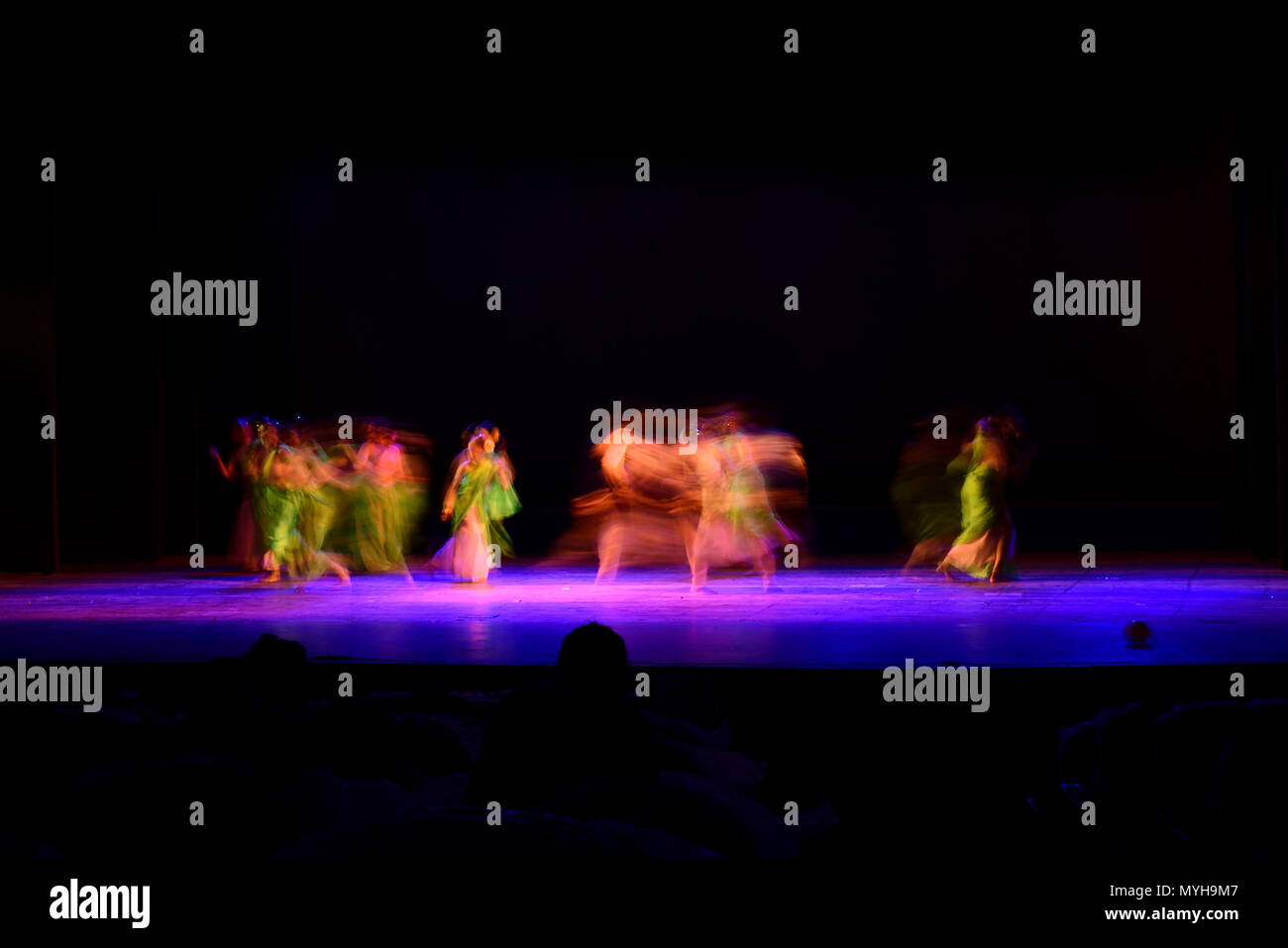 Un gruppo di persone che ballano sul palco su sfondo nero. Foto Stock