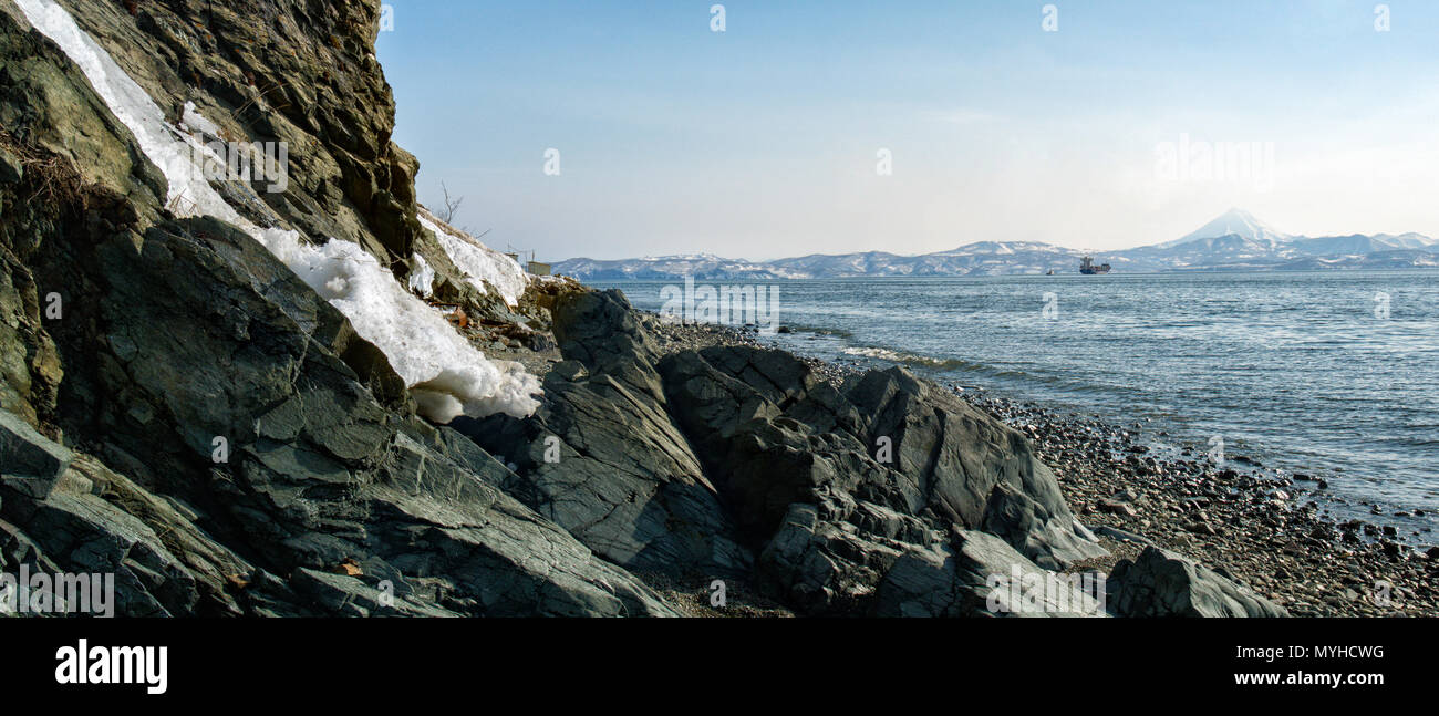 Vista della Baia Avacha, vulcani, coperta di neve sulle colline pietrose, shore, navi nella città di Petropavlovsk-Kamchatsky in aprile Foto Stock