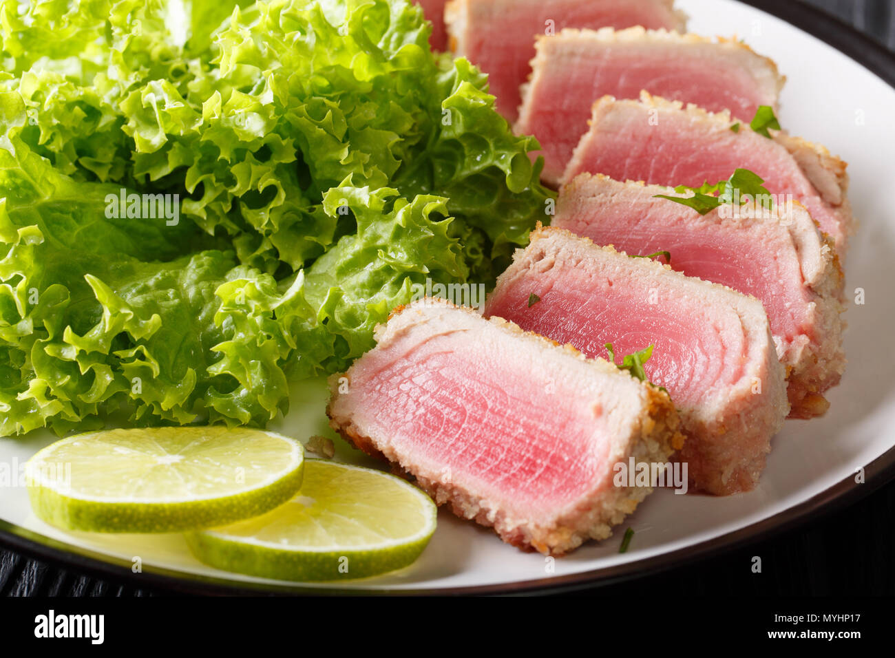 Bistecca di tonno in panatura Panko con lattuga e calce closeup su una piastra orizzontale. Foto Stock