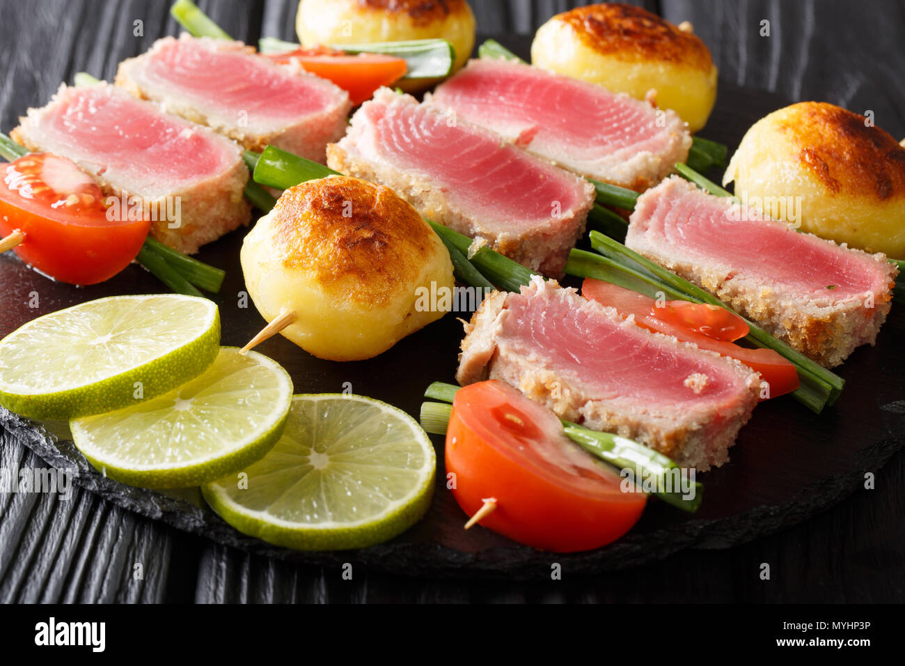 Cucinato al momento shish kebab di tonno fresco, pomodori, patate e cipolle verdi vicino sul tavolo orizzontale. Foto Stock