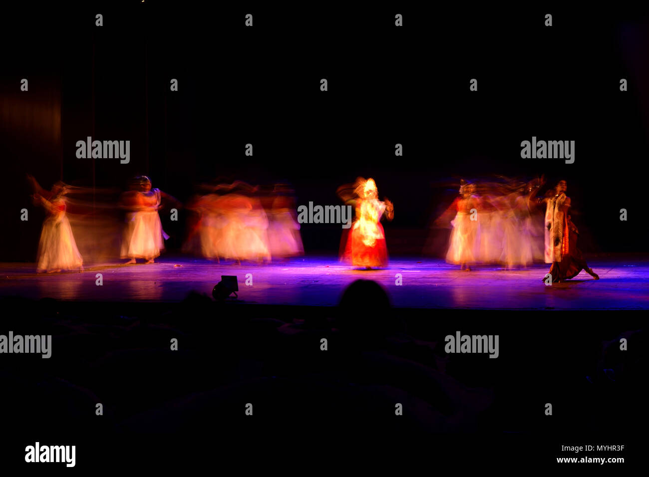 Un gruppo di persone che ballano sul palco su sfondo nero. Foto Stock