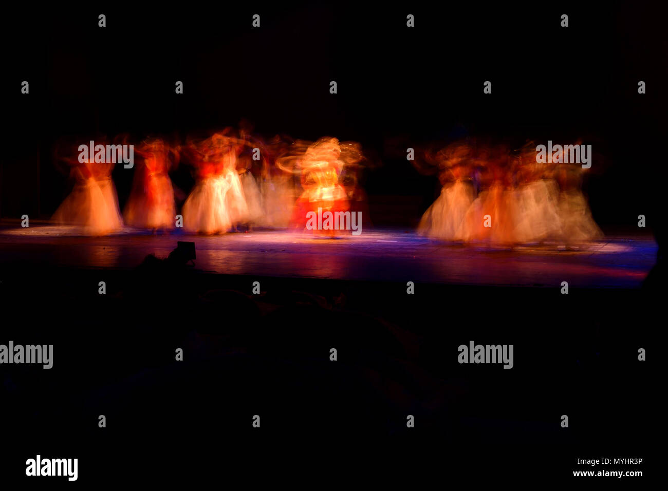 Un gruppo di persone che ballano sul palco su sfondo nero. Foto Stock