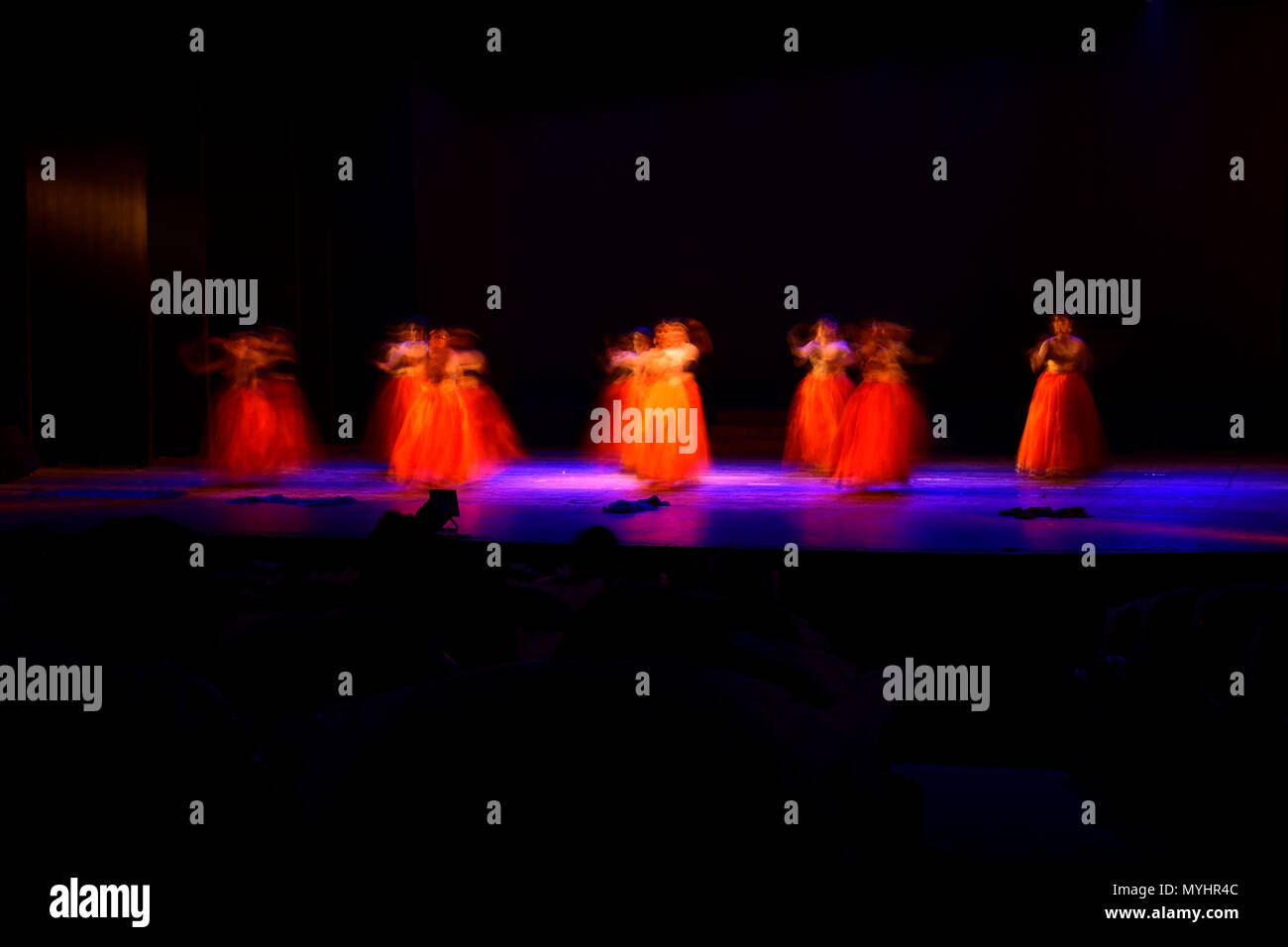 Un gruppo di persone che ballano sul palco su sfondo nero. Foto Stock