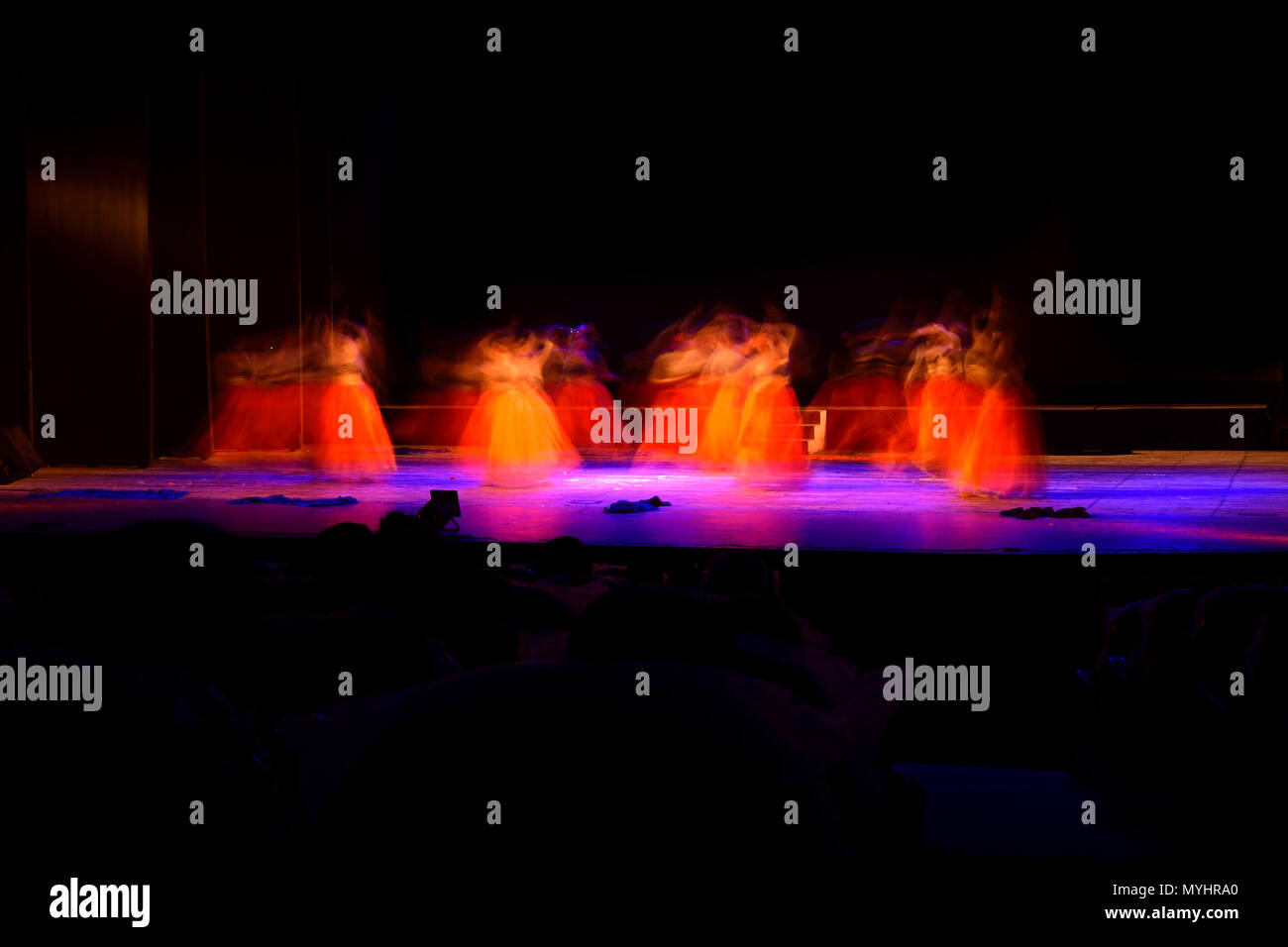 Un gruppo di persone che ballano sul palco su sfondo nero. Foto Stock