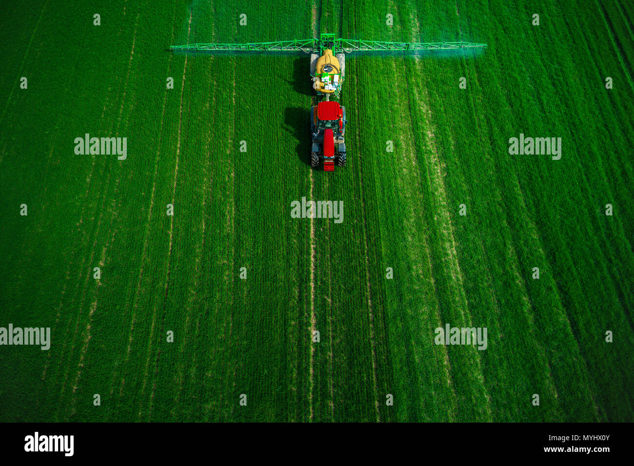 Vista aerea della trattrice agricola l'aratura e l'irrorazione sul campo. Foto Stock