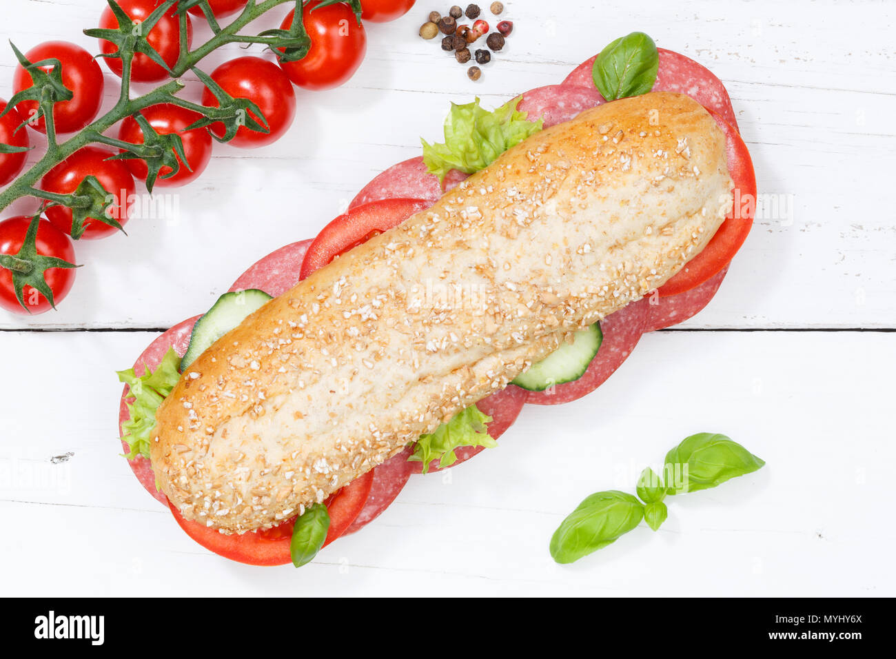 Sub tutto il sandwich di grani di grano baguette con salame di sopra sulla tavola di legno legno Foto Stock