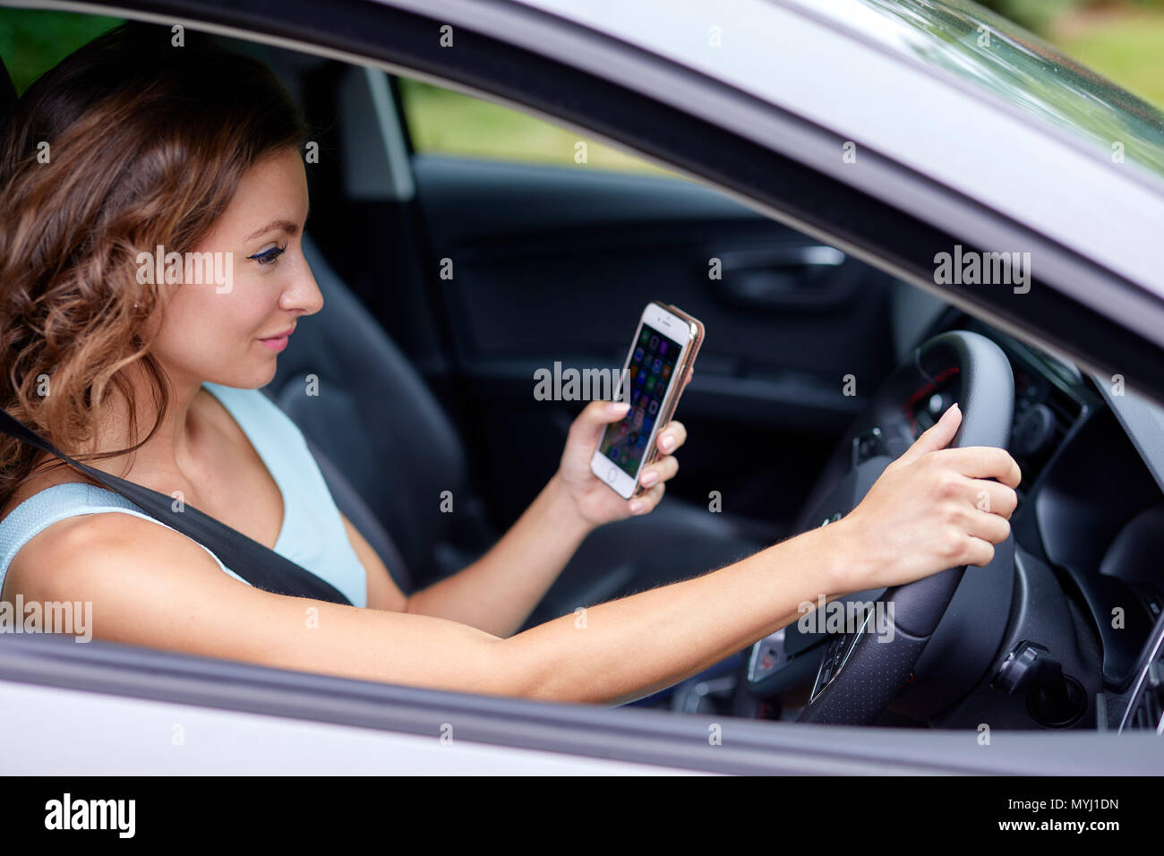 Donna alla guida mentre si utilizza il telefono cellulare Foto Stock