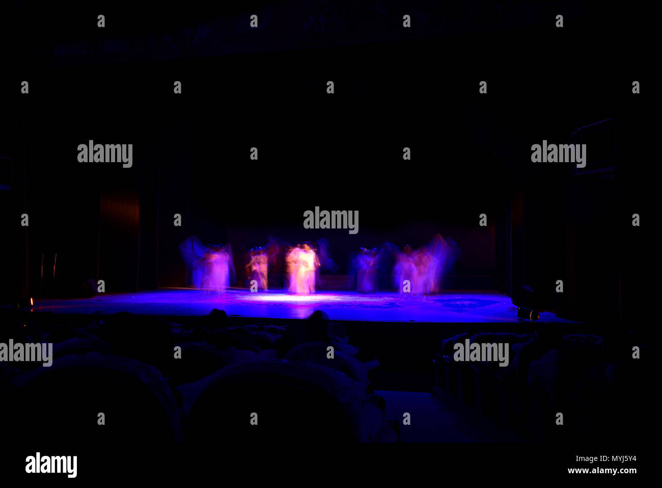 Un gruppo di persone che ballano sul palco su sfondo nero. Foto Stock