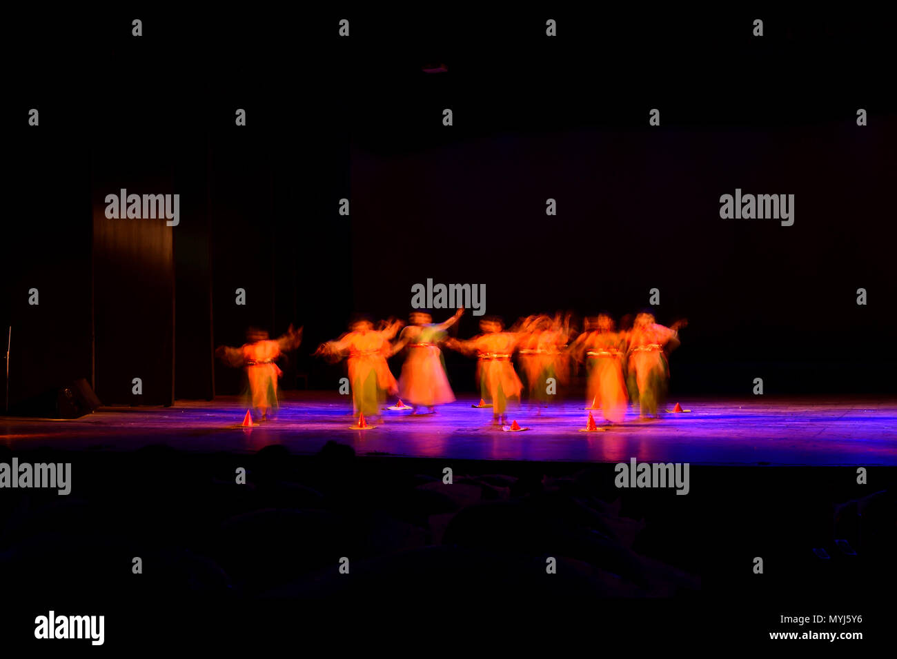 Un gruppo di persone che ballano sul palco su sfondo nero. Foto Stock