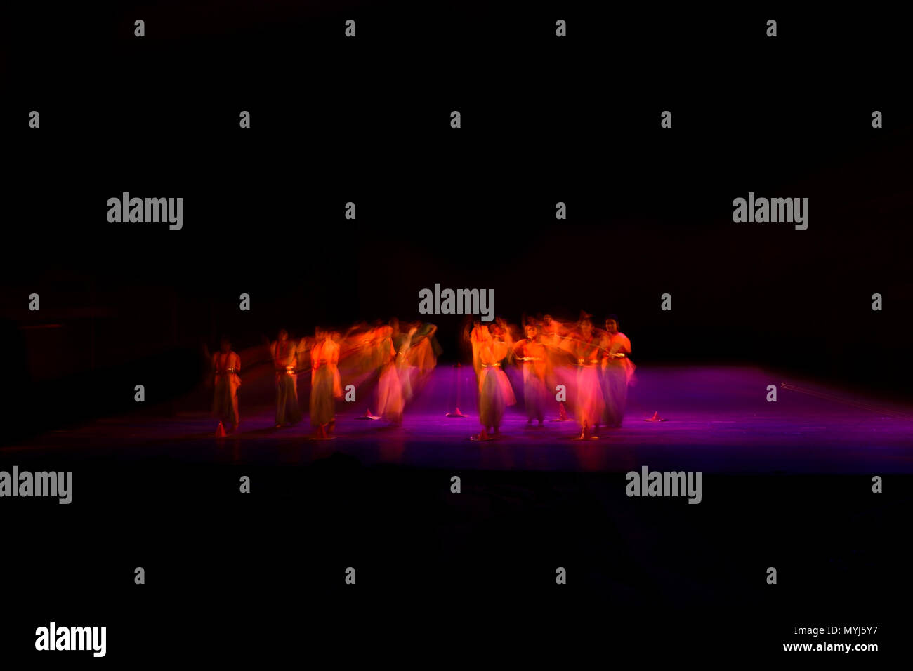 Un gruppo di persone che ballano sul palco su sfondo nero. Foto Stock