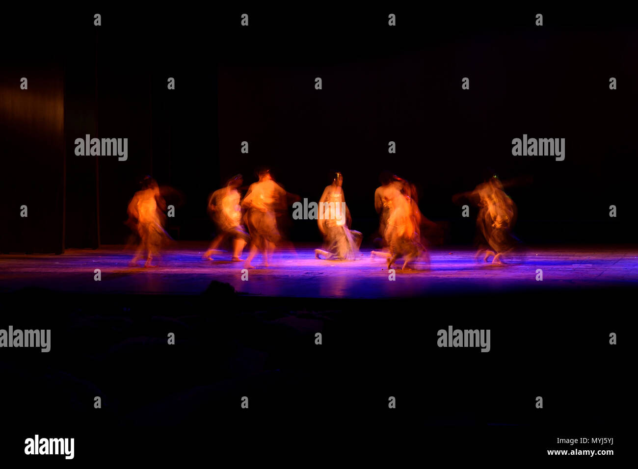 Un gruppo di persone che ballano sul palco su sfondo nero. Foto Stock
