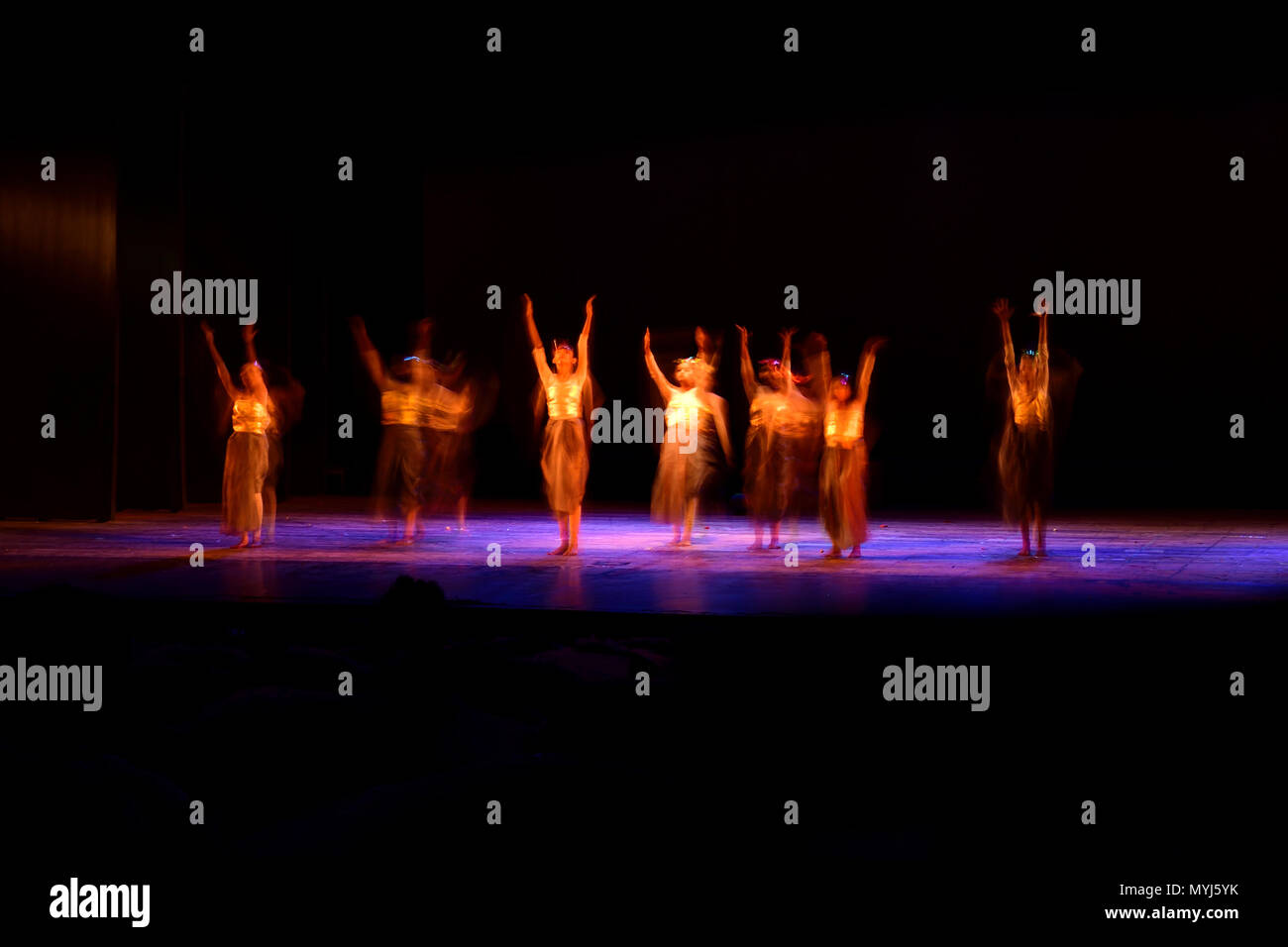 Un gruppo di persone che ballano sul palco su sfondo nero. Foto Stock