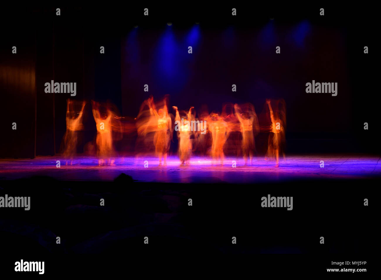 Un gruppo di persone che ballano sul palco su sfondo nero. Foto Stock