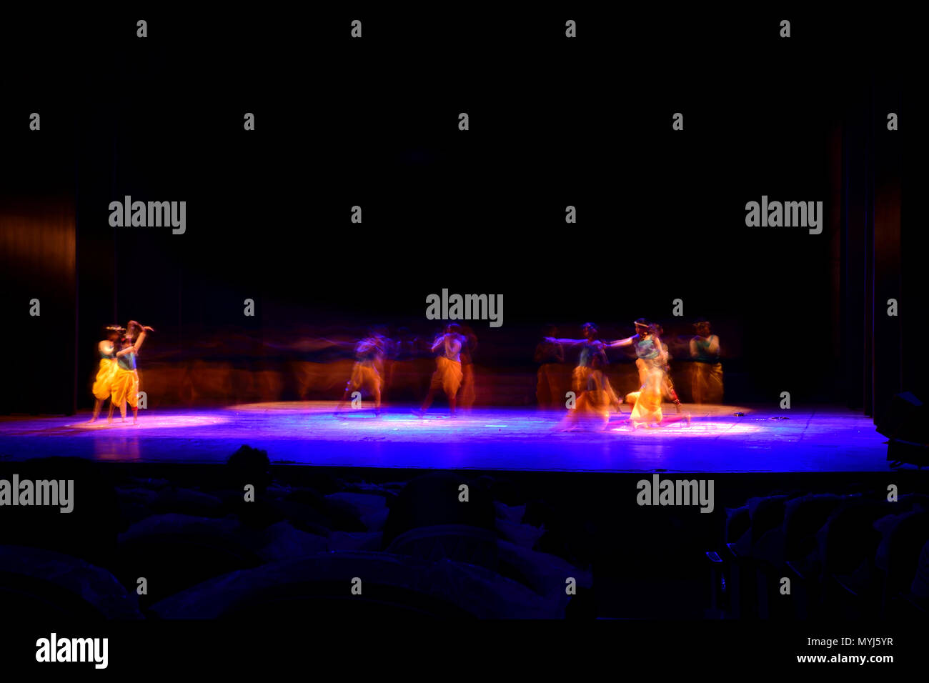 Un gruppo di persone che ballano sul palco su sfondo nero. Foto Stock