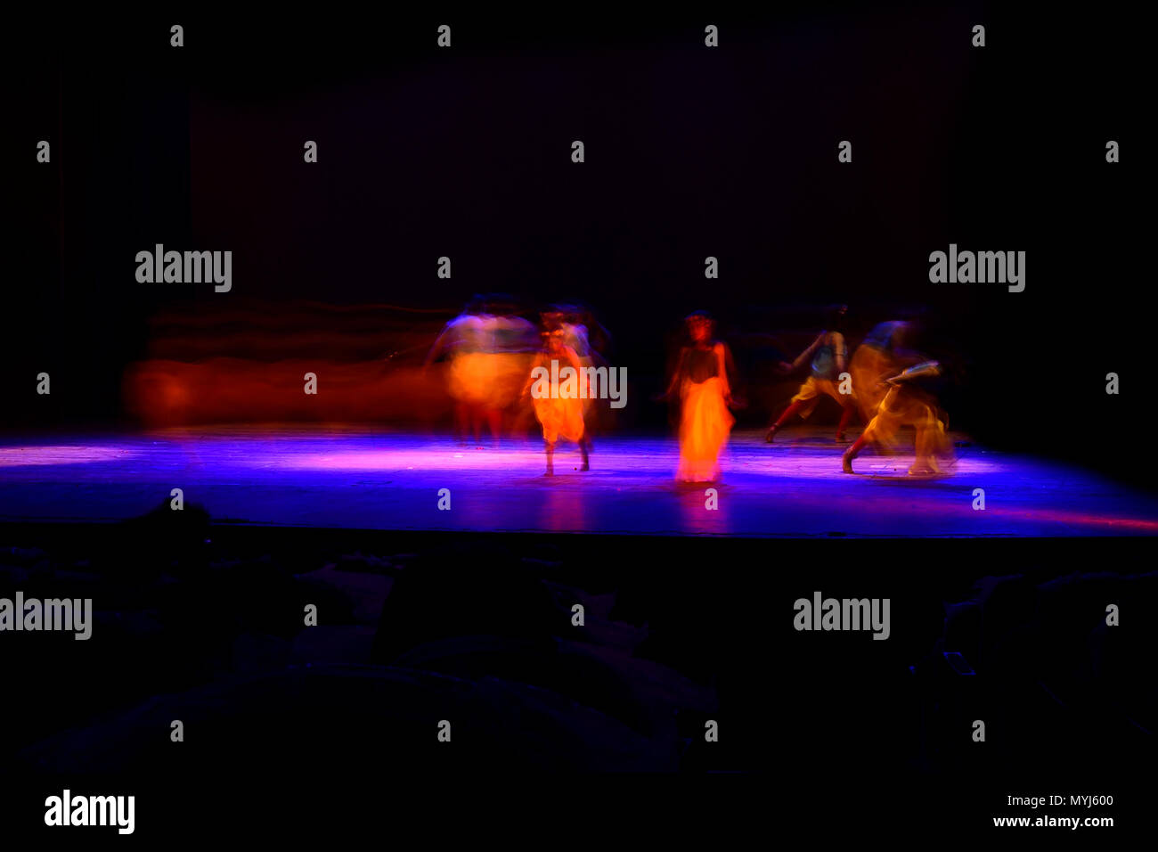 Un gruppo di persone che ballano sul palco su sfondo nero. Foto Stock