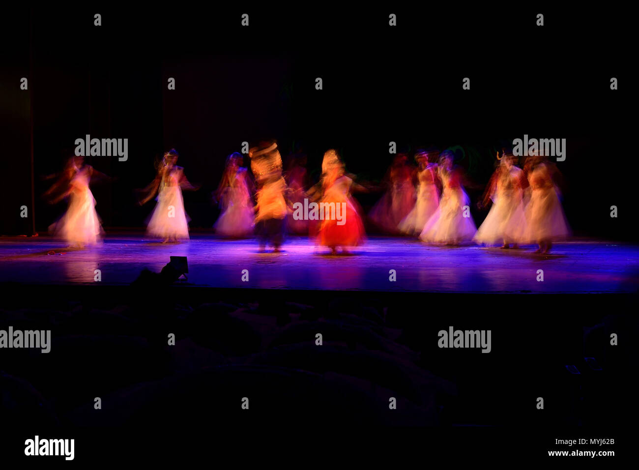 Un gruppo di persone che ballano sul palco su sfondo nero. Foto Stock