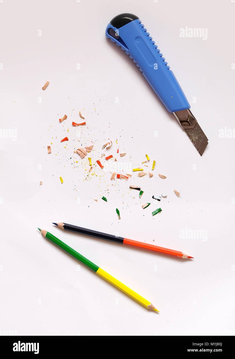 Piatto di laici matite di colore e una blu coltello con matita colorata trucioli sparse su un libro bianco sullo sfondo. Foto Stock