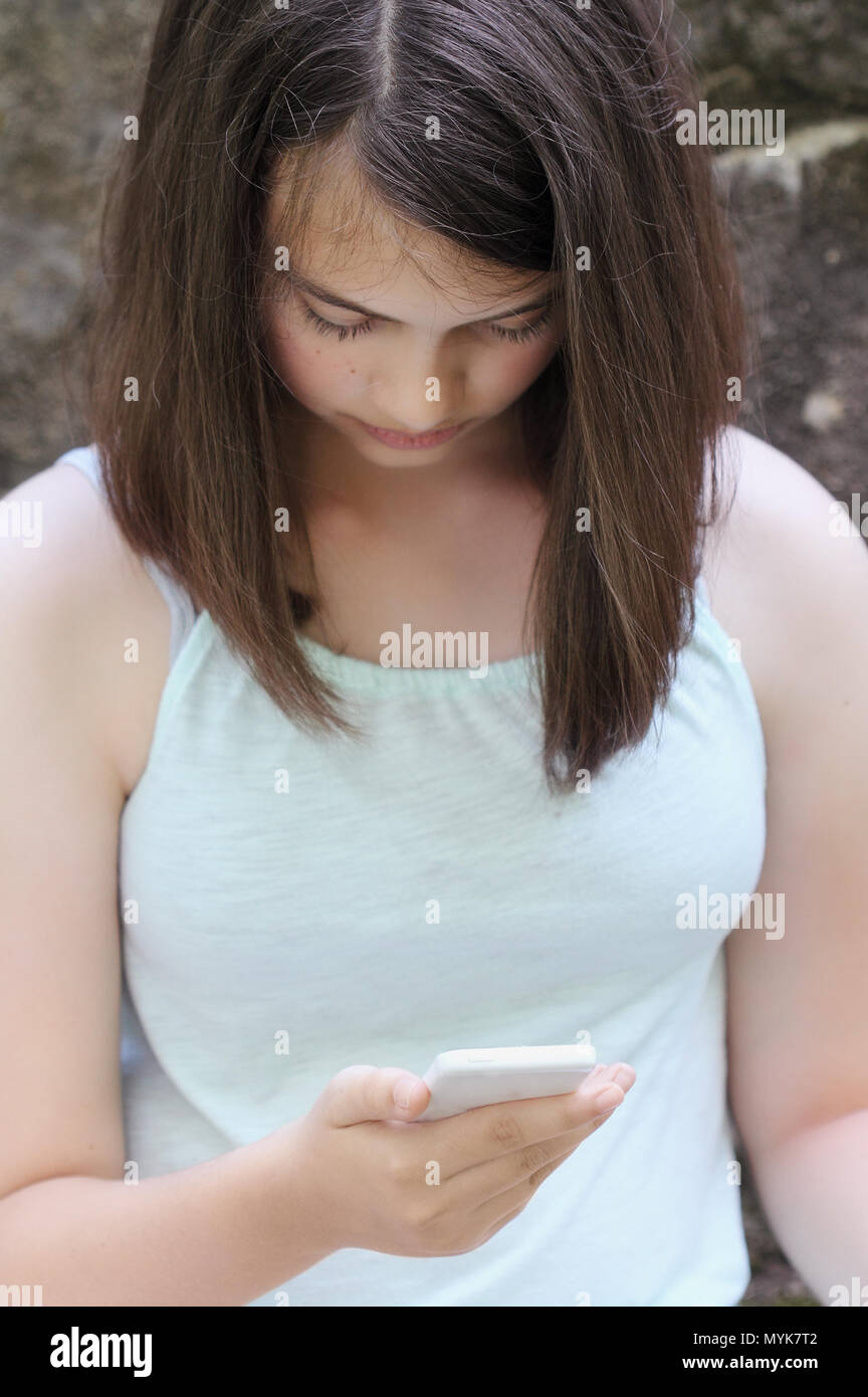Giovane ragazza adolescente la lettura di un messaggio di testo sullo smartphone. Messa a fuoco selettiva su teen la mano che tiene il telefono. Foto Stock
