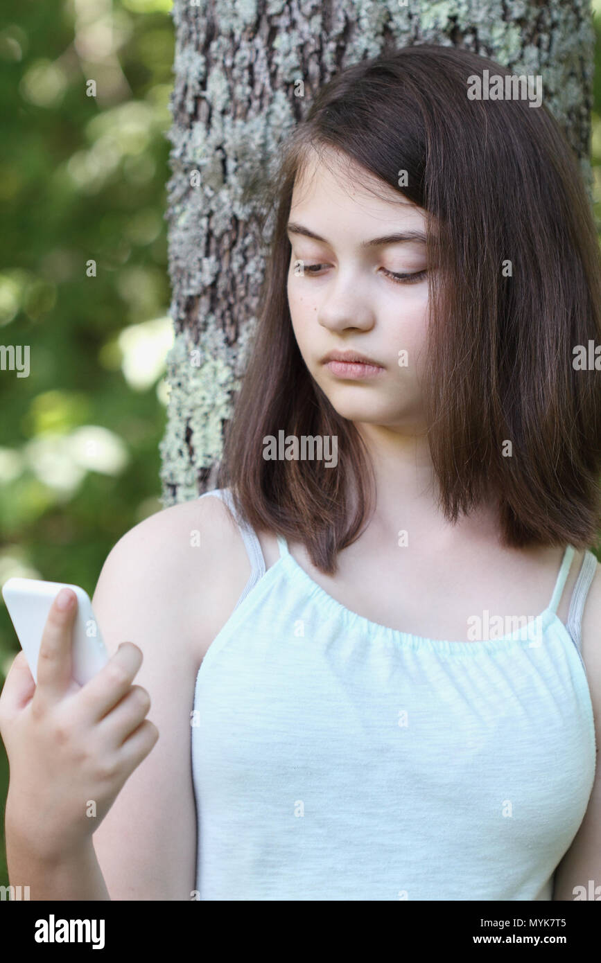 Infelice giovane ragazza adolescente la lettura di un messaggio di testo sullo smartphone. Foto Stock