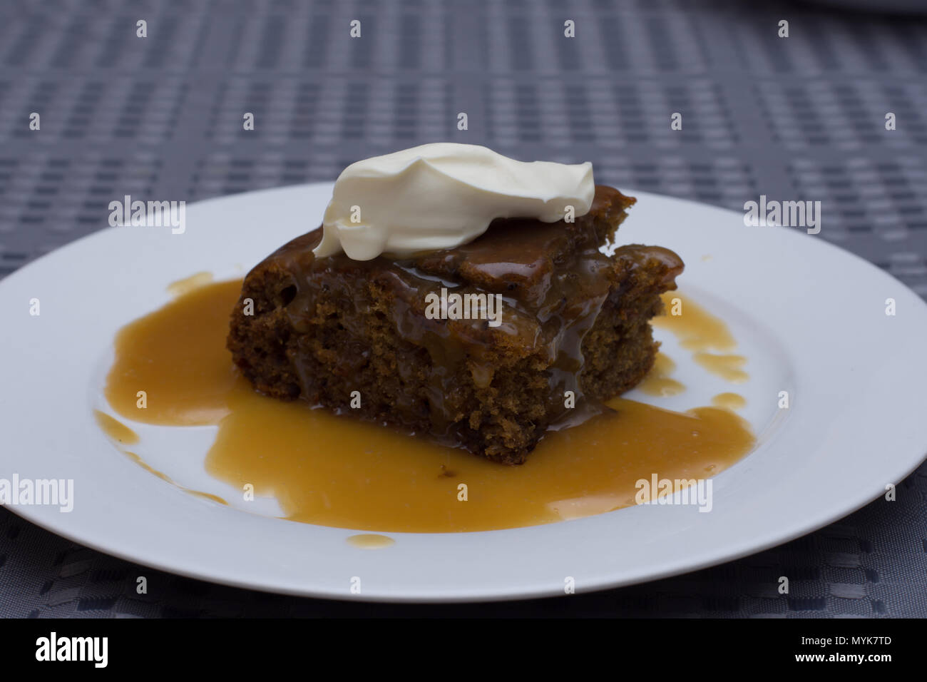 Sticky Date pudding con salsa di caramello e rabboccato con crema di latte Foto Stock