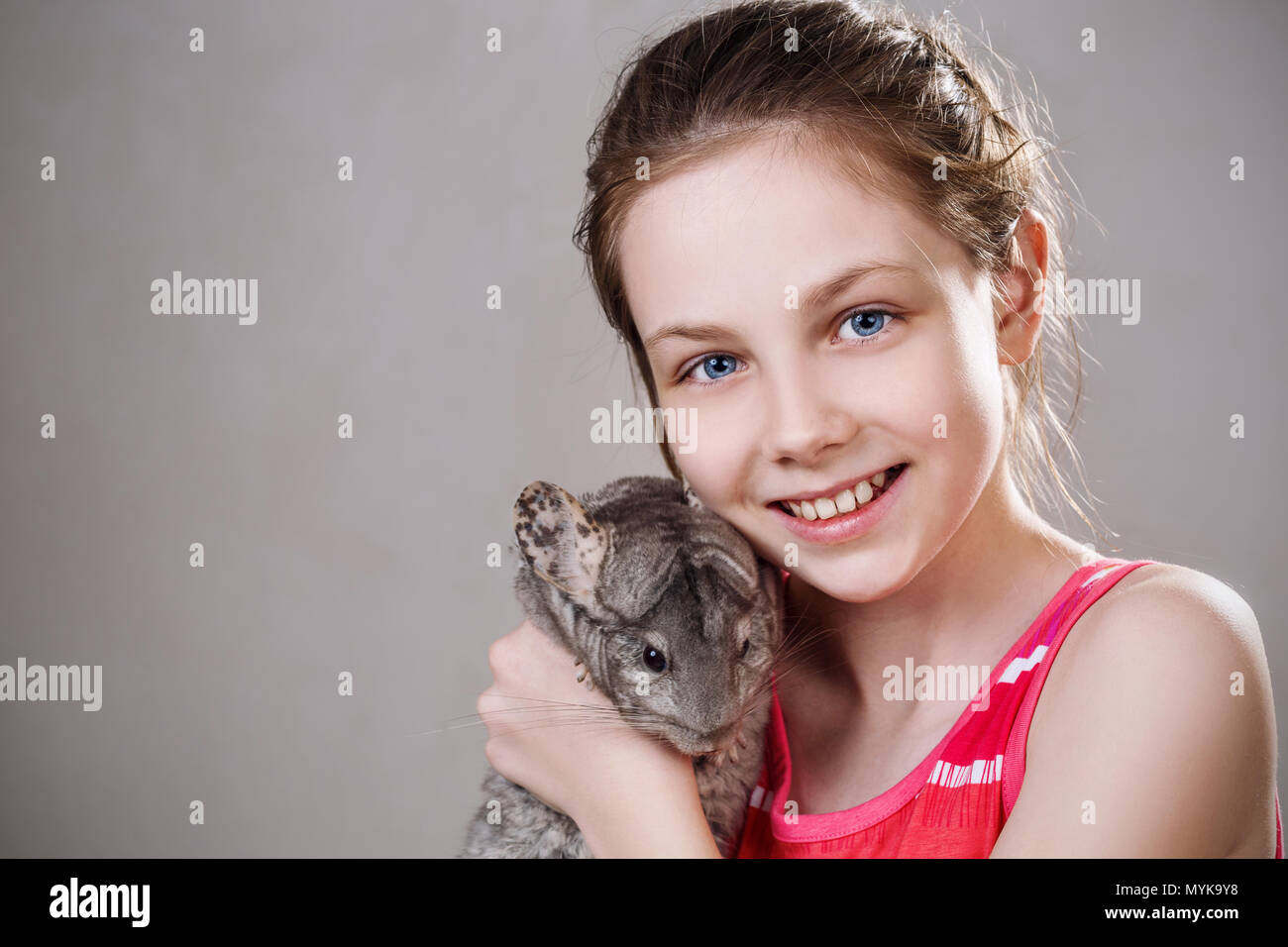 Carino sorridente bambina detiene funny grigio chinchilla. Foto Stock