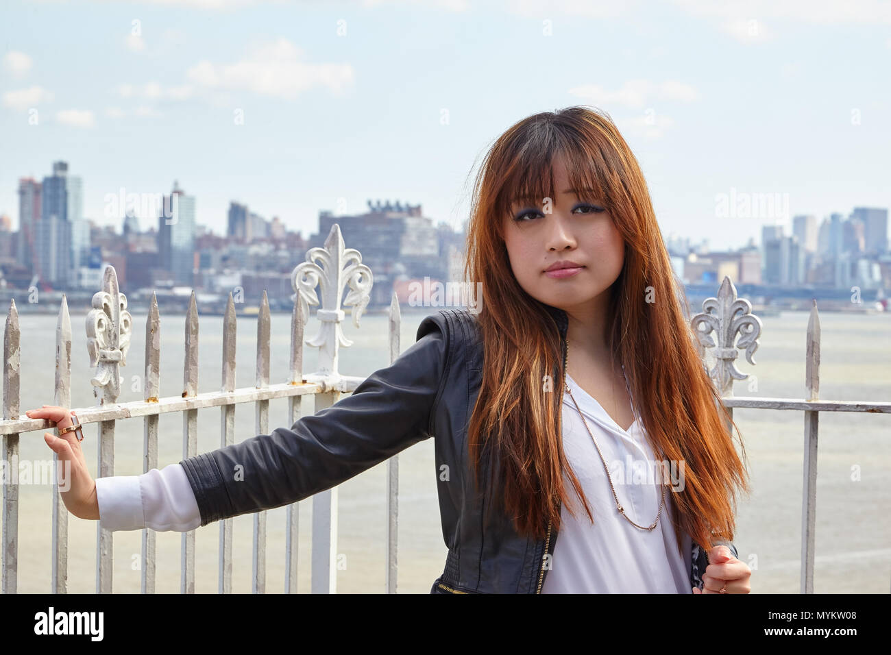 Donna asiatica in giacca di pelle in piedi di fronte a skyline della città Foto Stock