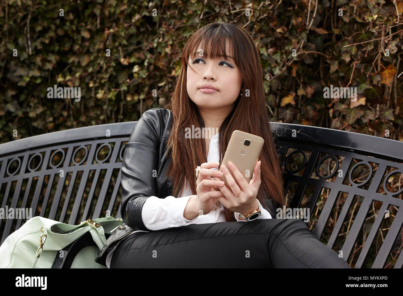 Donna asiatica tramite cellulare al di fuori Foto Stock