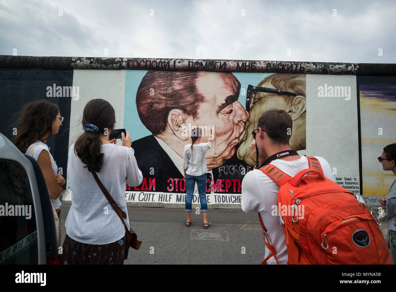 Berlino. Germania. I turisti posano per le foto di fronte una delle restanti sezioni del muro di Berlino all'East Side Gallery. I turisti pongono per ph Foto Stock