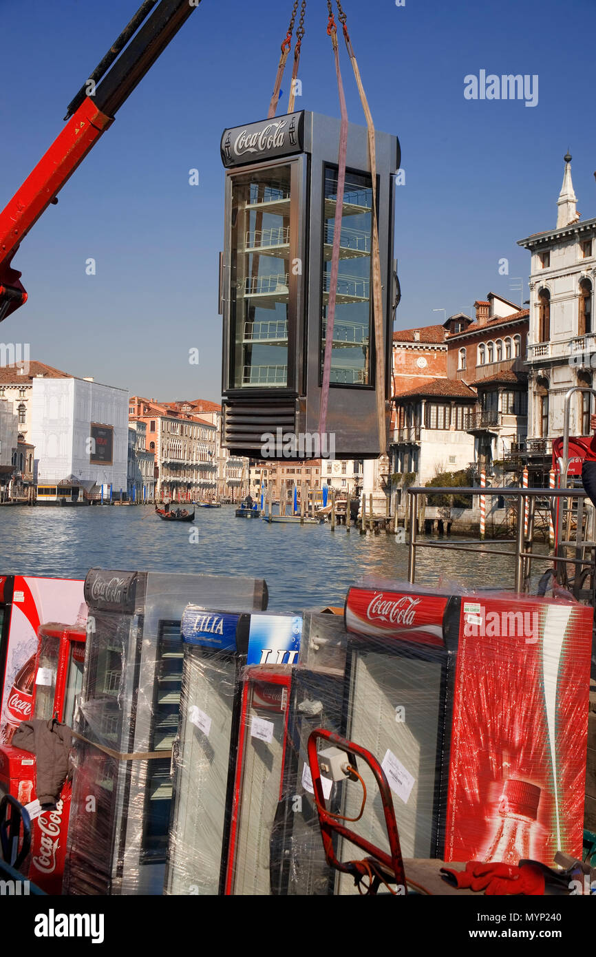 Vista bizzarro di coca cola macchine essendo off-caricato da una chiatta sul Canal Grande dal Campo de la carità al di fuori dell'Accademia di Venezia, Italia Foto Stock