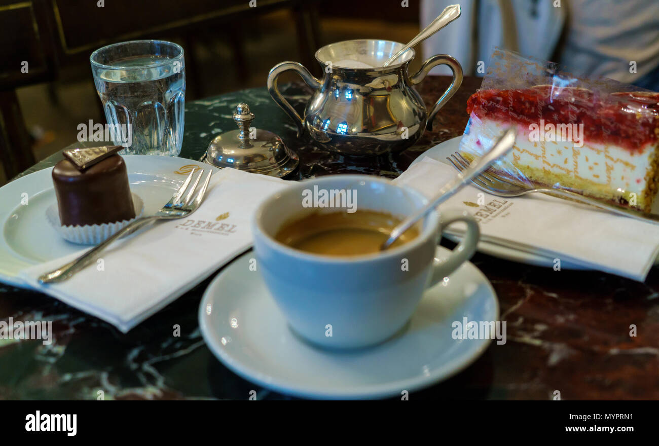 Vienna, Austria - 22 Ottobre 2017: sul tavolo della famosa pasticceria cafè Demel ci sono ciliegia torta, mini torta Sacher e tazza da caffè con es Foto Stock