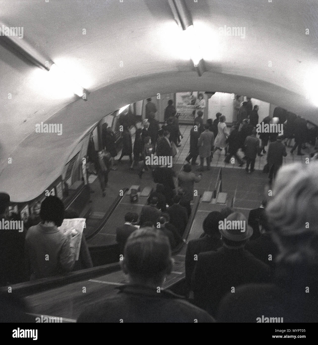 Anni '60, storici, persone che scendono le scale mobili in legno sulla metropolitana di Londra, la metropolitana o il sistema di trasporto di massa per la città di Londra, per arrivare alle piattaforme per salire a bordo dei treni. Foto Stock