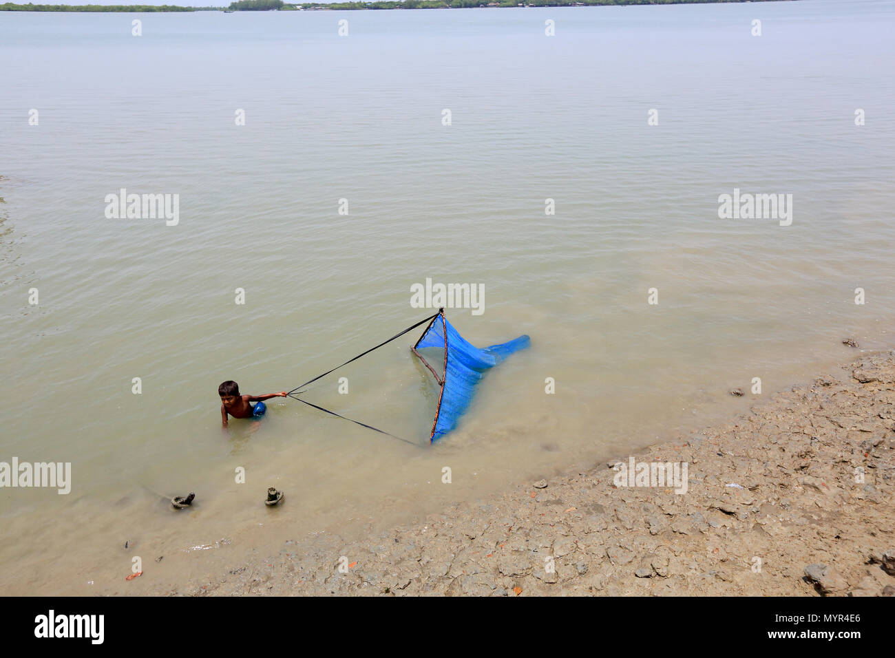 Un bambino la cattura di gamberetti bambino sul fiume Kholpetua a Gabura vicino Sundarbans. Satkhira, Bangladesh. Foto Stock