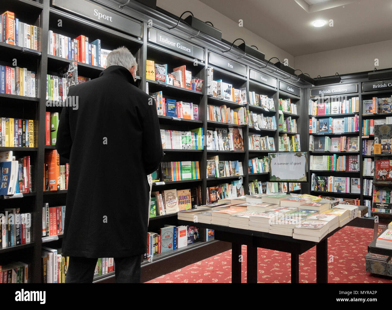 Vista posteriore di uomo maturo della lettura in Waterstones bookshop. Regno Unito Foto Stock