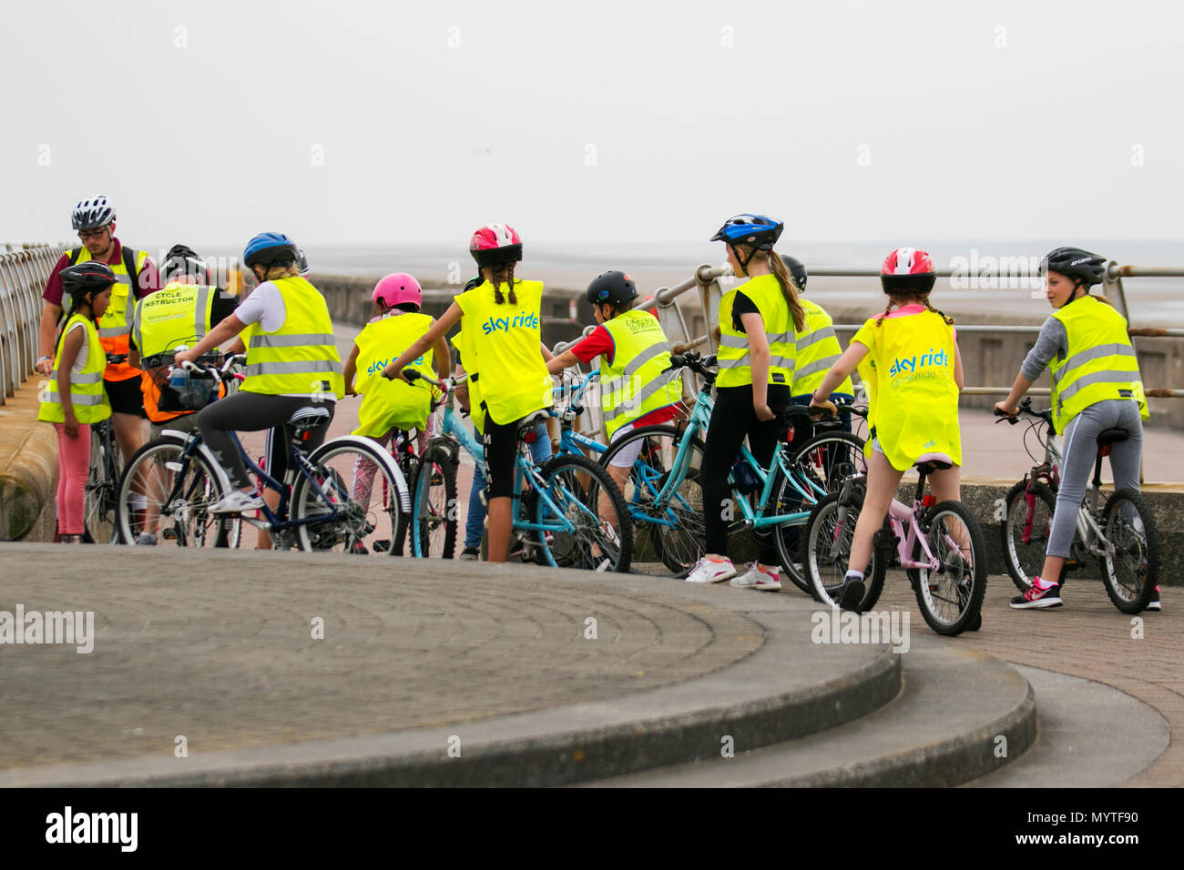 Giri guidati Sky Ride e lezioni di ciclismo a Blackpool, Regno Unito. Questi gruppi di bambini che indossano abiti riflettenti i bambini insegnanti, spesso di circa 20 persone, escono a cavallo con un British Cycling Ride leader, un pilota esperto e ben addestrato che conduce i bambini su un percorso appositamente selezionato, spesso fuori strada, creando fiducia e divertimento sulla bicicletta. Foto Stock