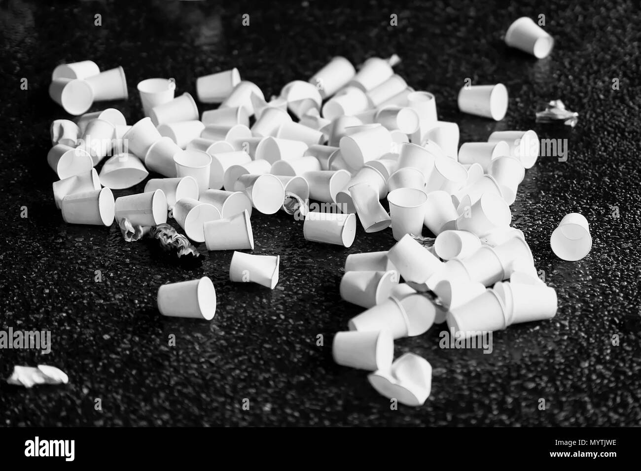 Pila di usato monouso di cartone bianco tazze per acqua su asfalto, concetto ecologico di rifiuti e riciclaggio Foto Stock