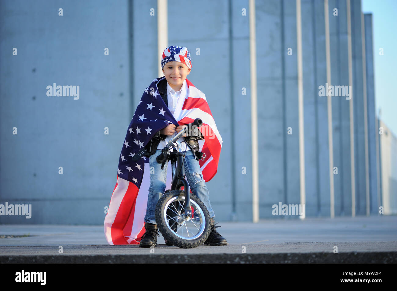 Felice bel ragazzo che sorride e sventola bandiera americana al di fuori, indossando Jackster bandana. Bambino festeggia 4 luglio - Giorno di Indipendenza degli Stati Uniti d'America. Foto Stock