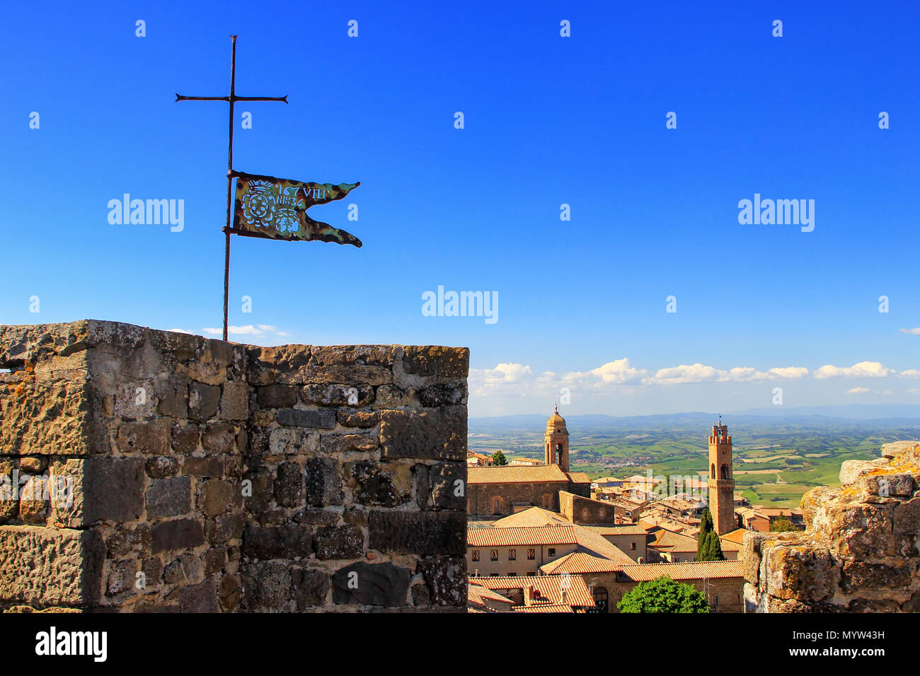 Bandiera di metallo sulla parte superiore della Fortezza di Montalcino torre in Val d'Orcia, Toscana, Italia. La fortezza fu costruita nel 1361 sopra il punto più alto della città. Foto Stock