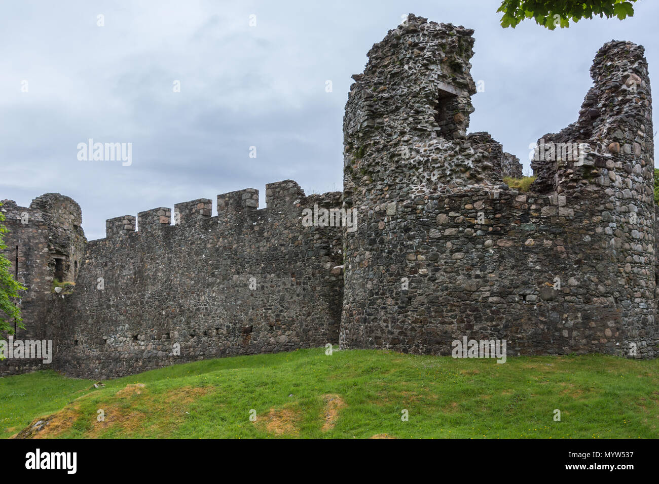 Torlundy, Scozia - Giugno 11, 2012: Comyn torre angolare in grigio-marrone pietra naturale muraglia difensiva con bastioni di Inverlochy Castle. Impostare sotto verde Foto Stock