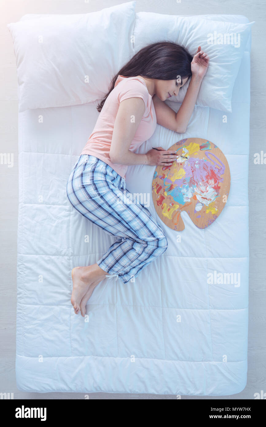 Ragazza di talento dormire nel letto con tavolozza e spazzola di pittura Foto Stock