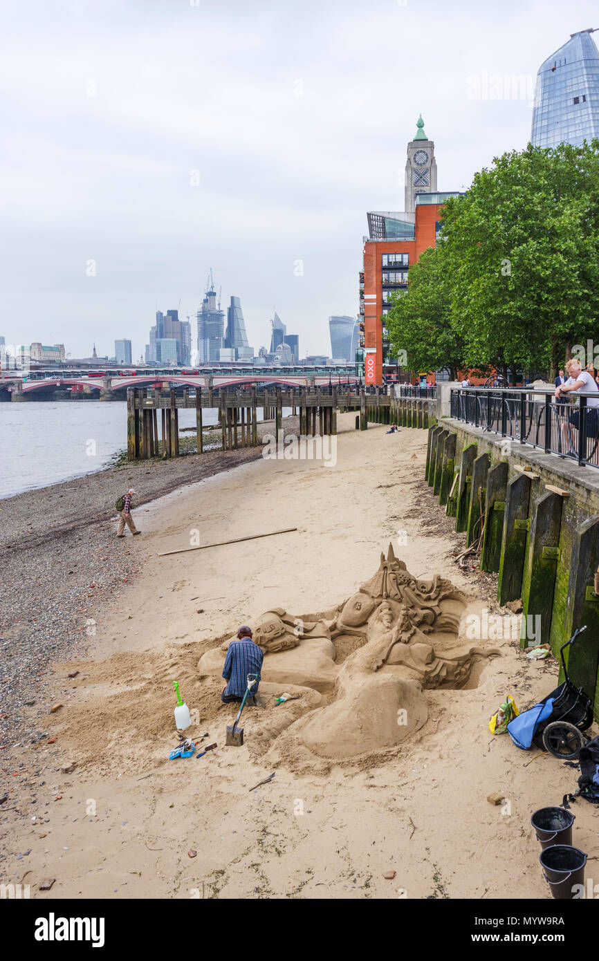 Scultore di sabbia lavorando su una scultura su una spiaggia a bassa marea lungo il fiume Tamigi, South Bank Embankment riverside walkvnear Oxo Tower Wharf, London SE1 Foto Stock