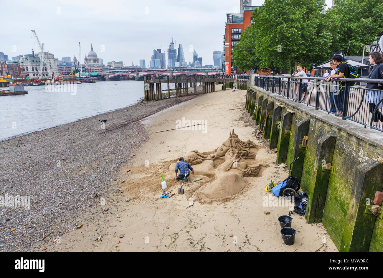 Scultore di sabbia lavorando su una scultura su una spiaggia a bassa marea lungo il fiume Tamigi, South Bank Embankment riverside walkvnear Oxo Tower Wharf, London SE1 Foto Stock